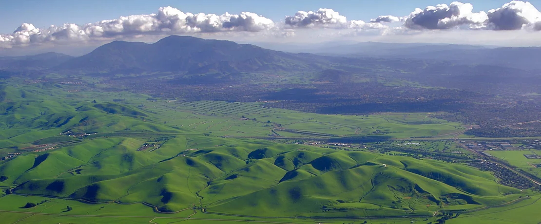 a green hills with a city in the distance