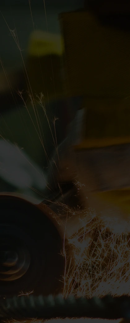 "Worker using a grinding tool with bright sparks flying in a workshop setting."