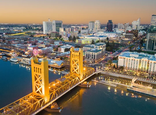 a bridge over water with buildings and a city in the background