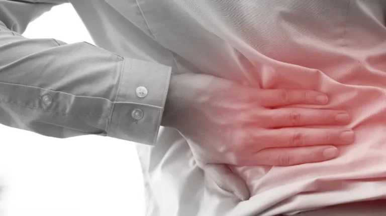 Person in light-colored shirt holding their lower back, highlighted with red to indicate pain.